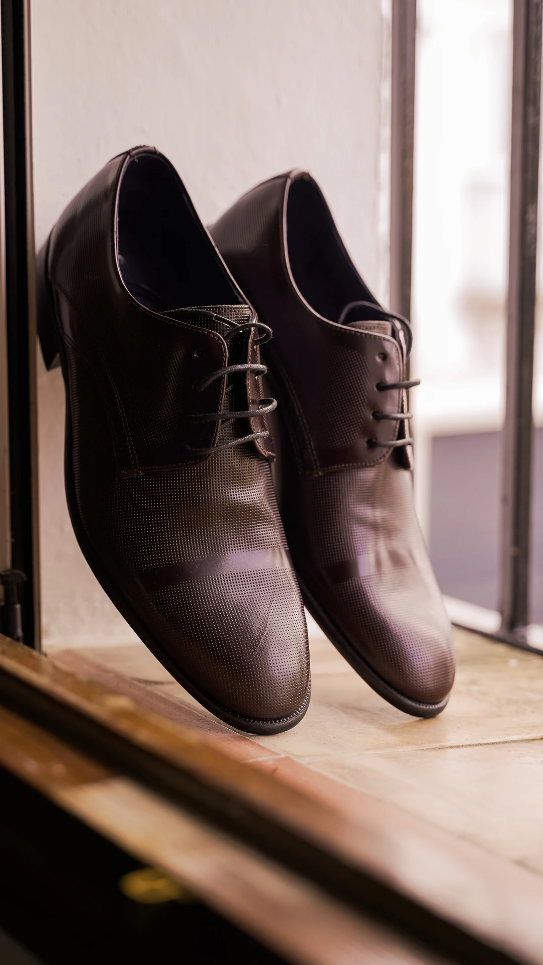 Zapatos del novio junto a una ventana
