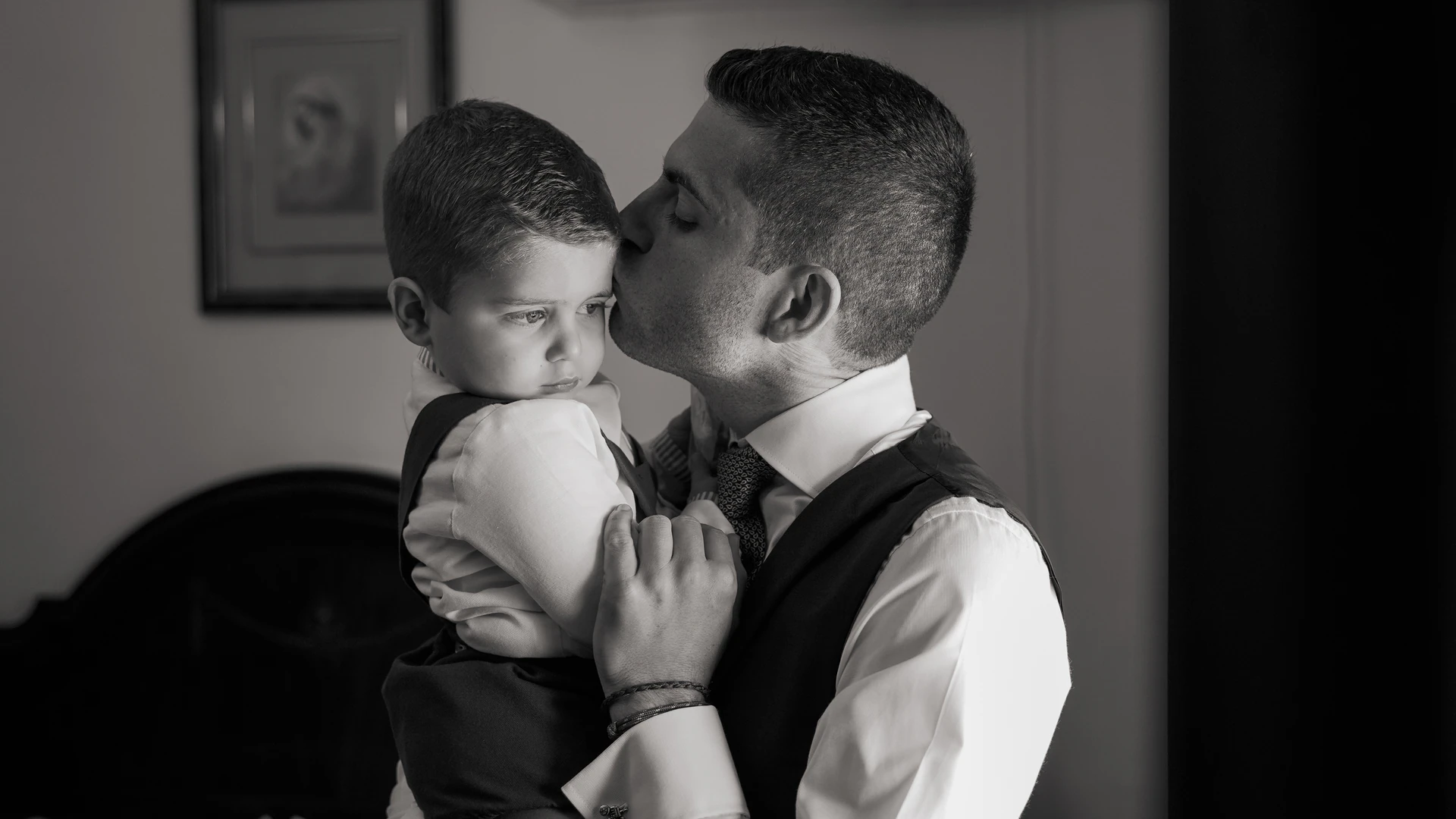El novio besa a un niño que lleva en brazos, en blanco y negro
