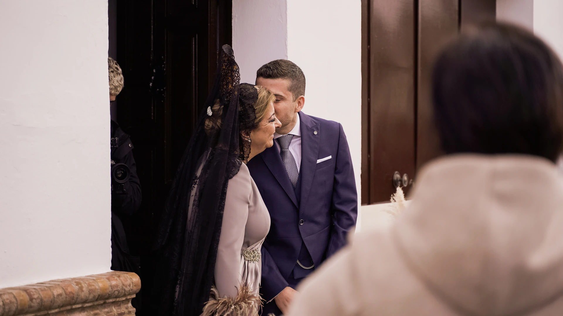 Una mujer con mantilla negra besa al novio antes de la ceremonia
