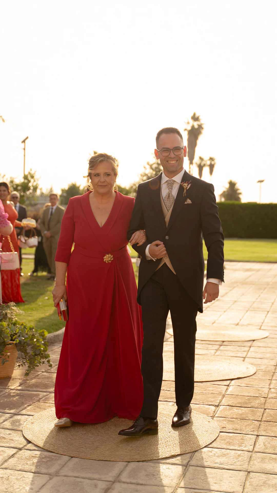 Jesús llega a la ceremonia del brazo de una mujer vestida de rojo