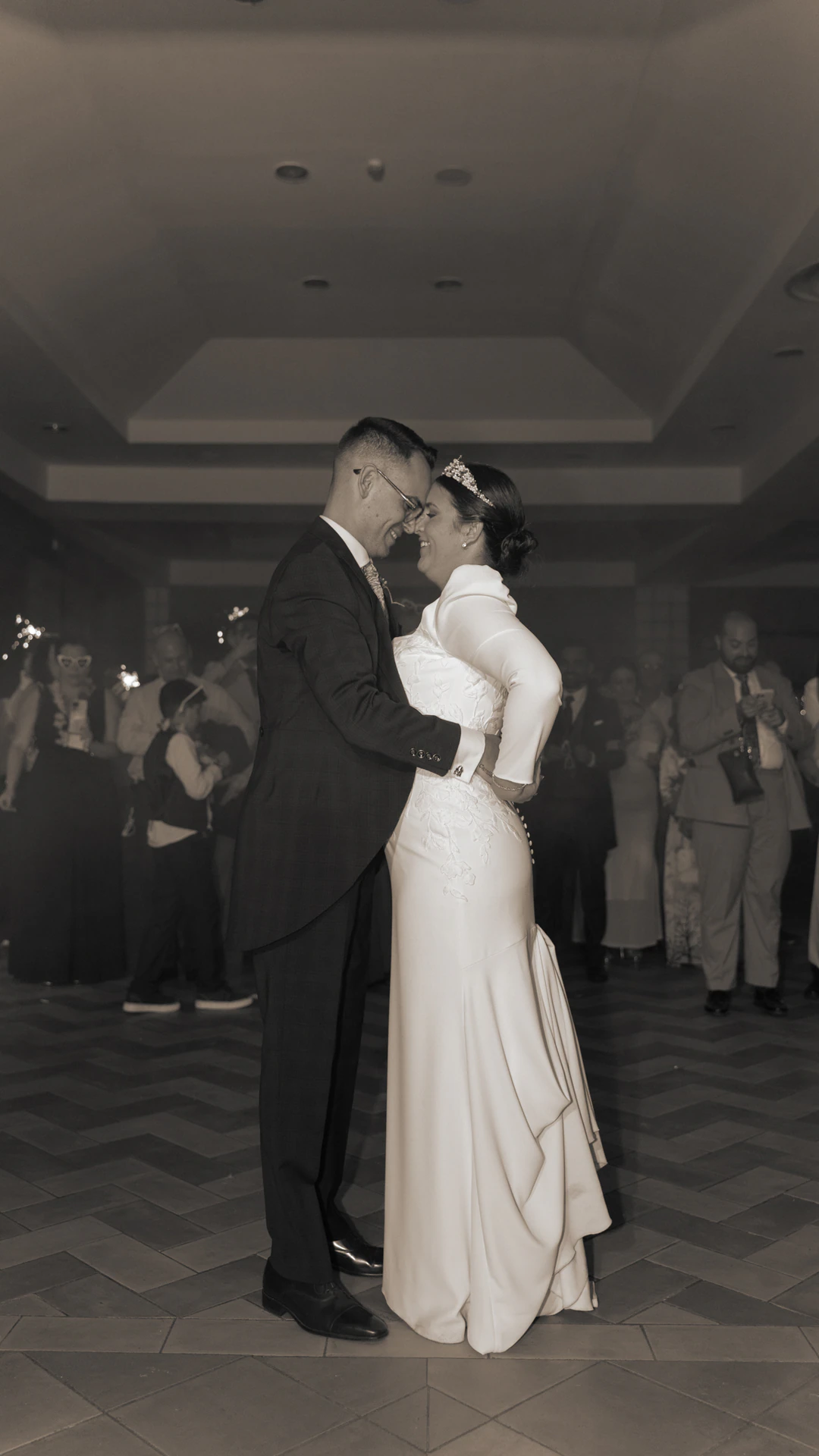 Jesús y Laura bailan rodeados de invitados, en blanco y negro