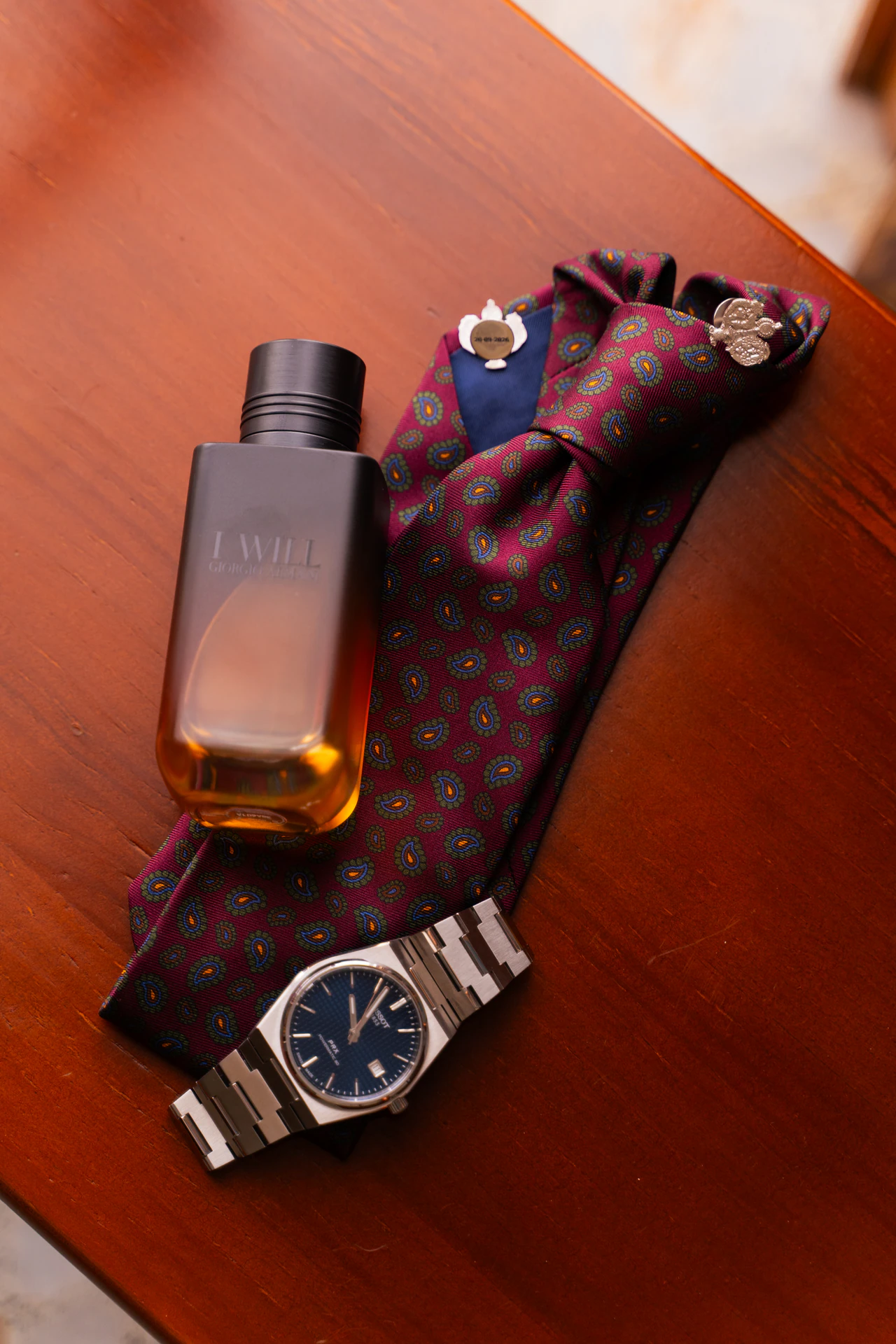 Perfume, corbata y reloj del novio sobre una mesa de madera