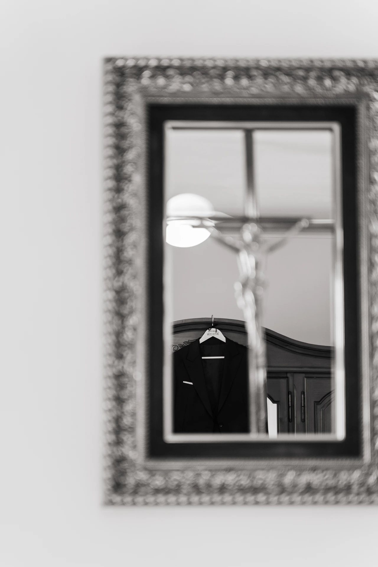 Un crucifijo reflejado en un espejo con marco plateado, en blanco y negro