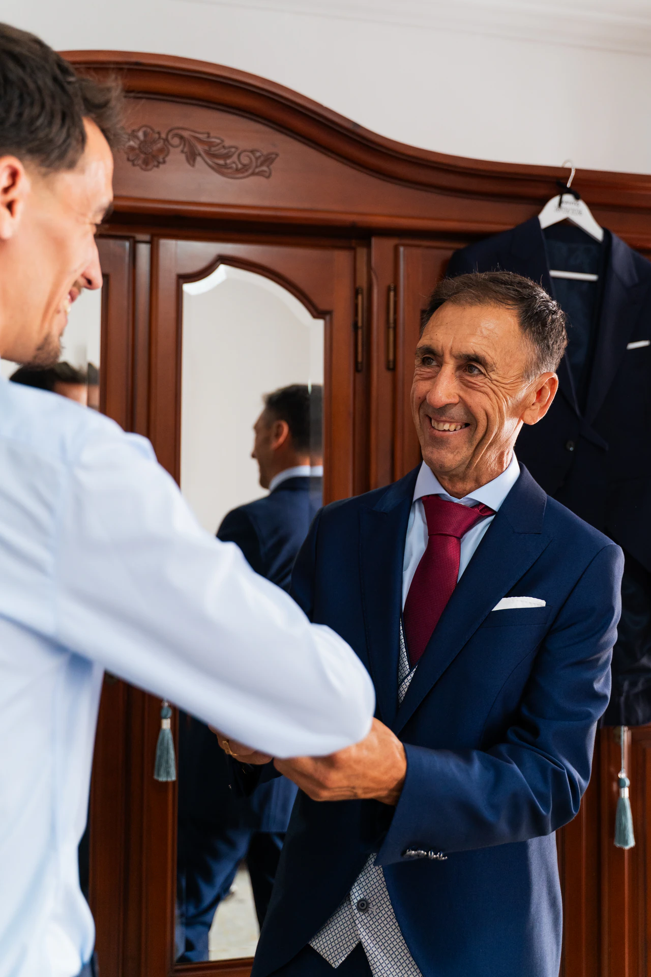 Juanma, en camisa, saluda a un hombre de traje y corbata roja