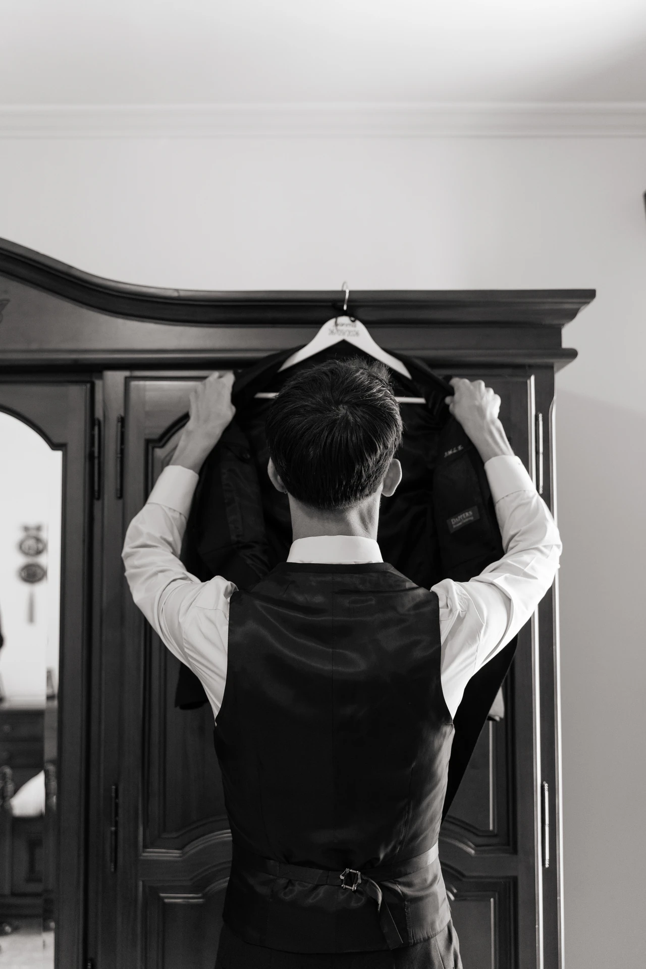 Juanma cuelga la chaqueta en el armario, en blanco y negro