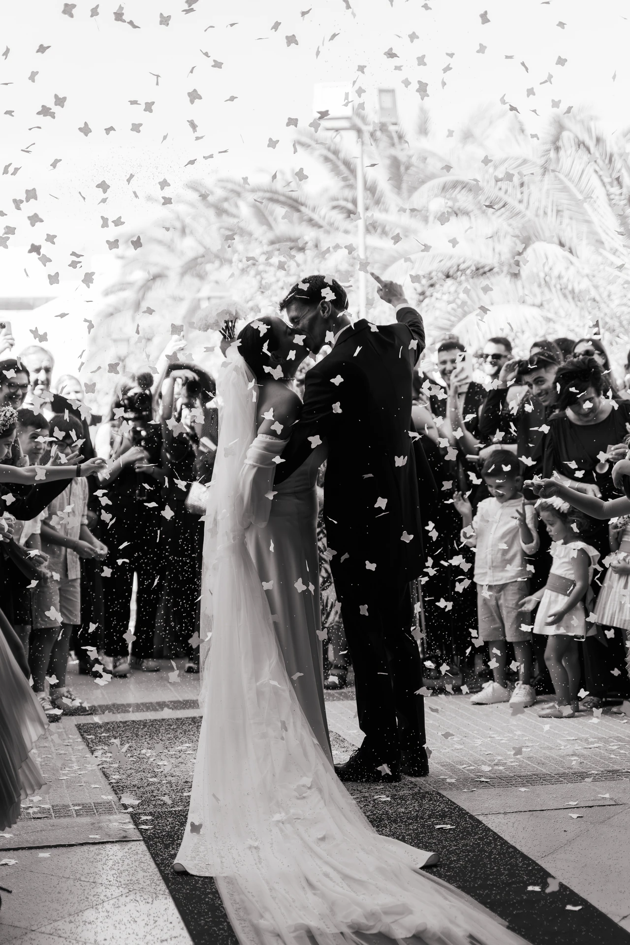 María y Juanma se besan bajo una lluvia de papelillos a la salida, en blanco y negro