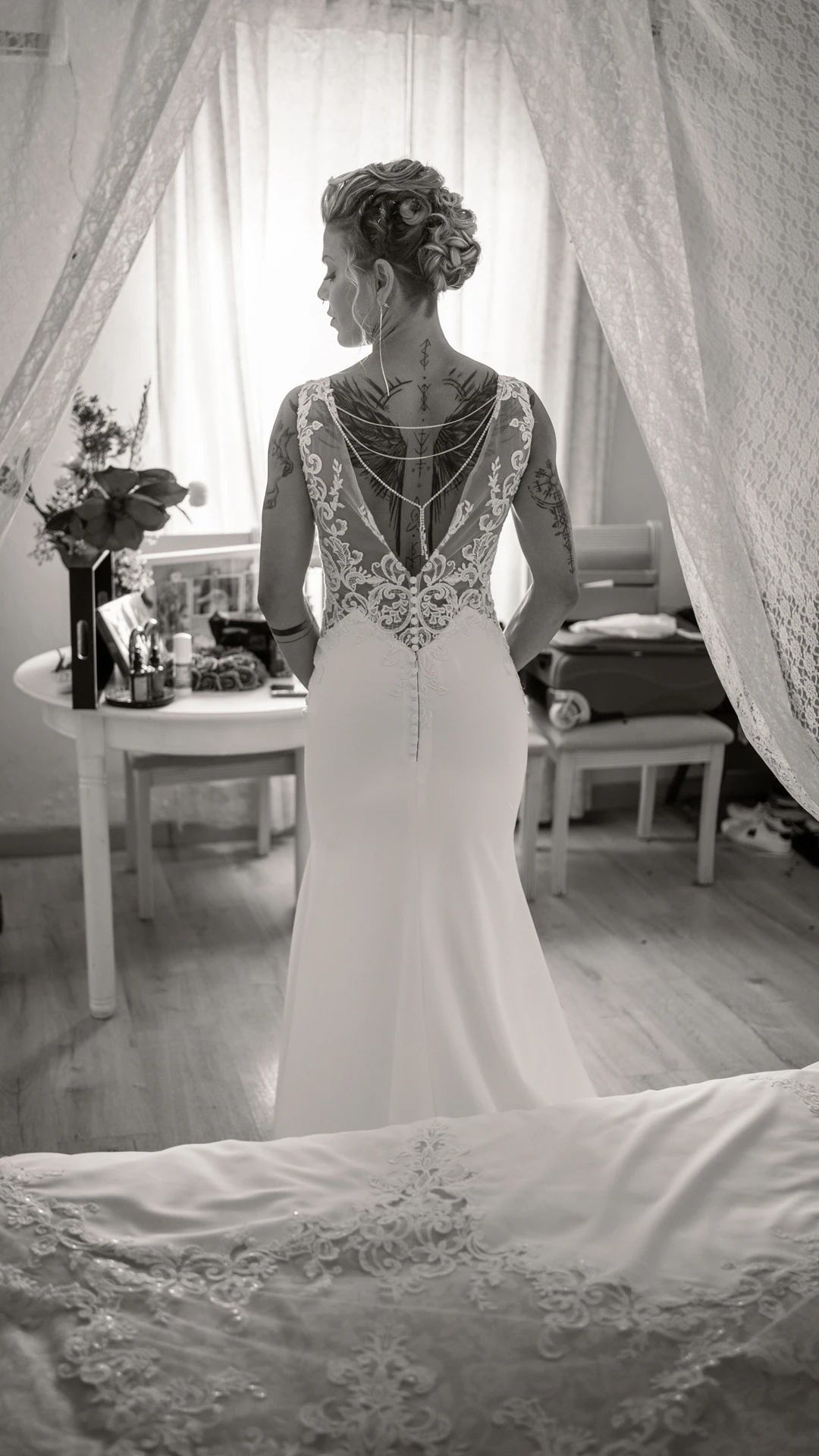 Una de las novias, de espaldas, con el vestido de espalda de encaje, en blanco y negro