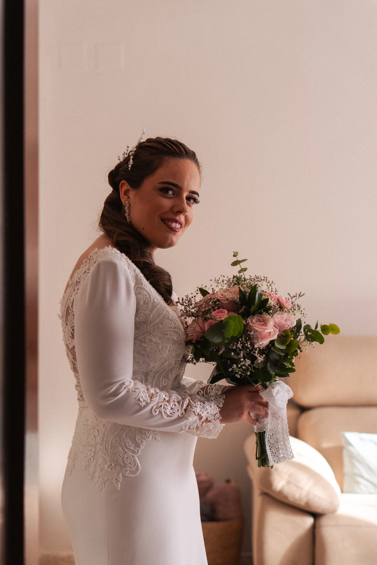 Una de las novias posa con su ramo en el salón de casa