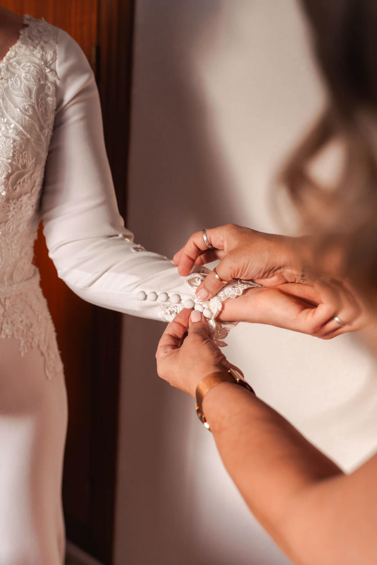 Le abrochan los botones de la manga del vestido