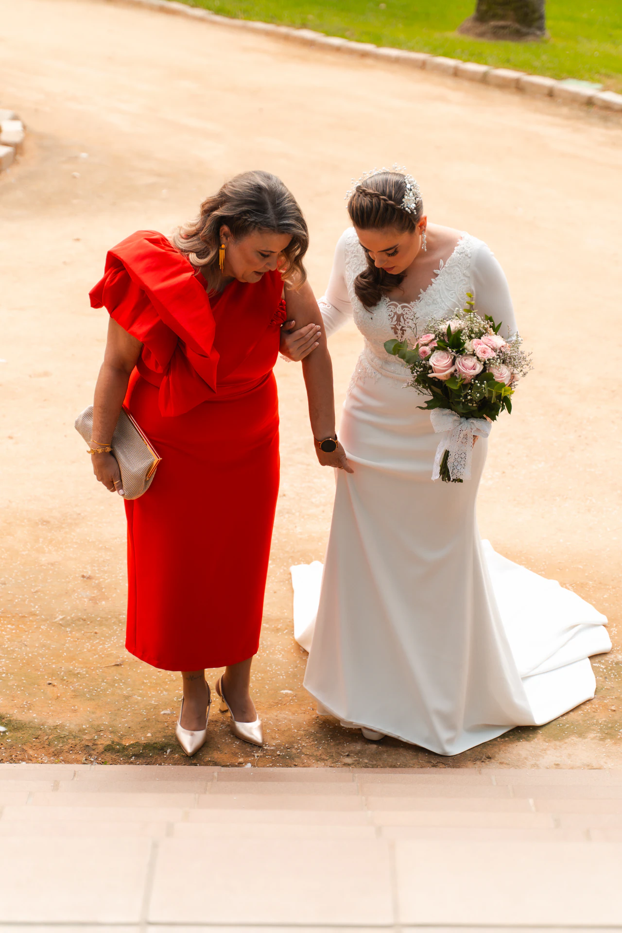 Una de las novias camina junto a una mujer vestida de rojo